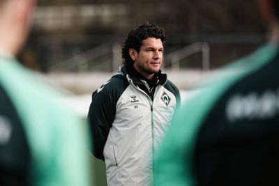 Nelson Valdez steht mit hinter dem Rücken verschränkten Armen vor einer Gruppe von Menschen.