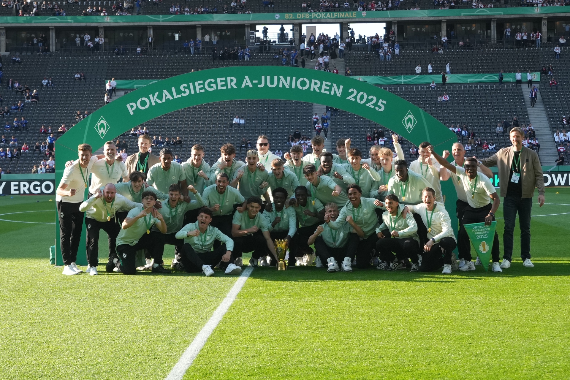 Die U19 steht zusammen vor einem Torbogen, auf dem Pokalsieger A-Junioren 2025 steht.