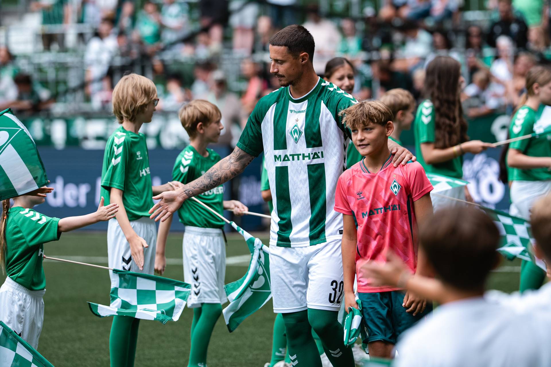 Marco Friedl klatscht Kindern ab und läuft ins Weserstadion ein.