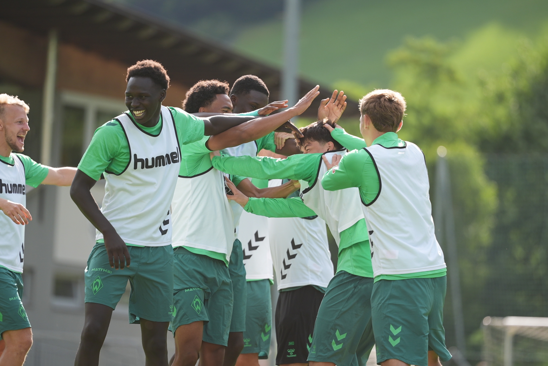 Eine Traube an Werder-Spielern jubelt auf dem Trainingsplatz.
