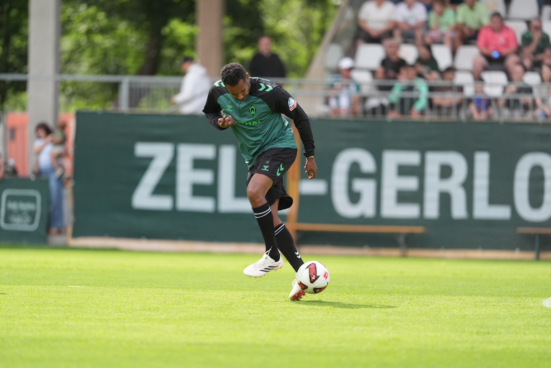 Daniel Thioune hält den Ball auf dem Trainingsplatz hoch.