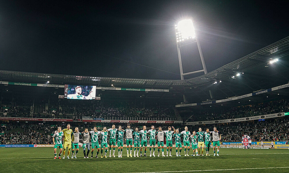 Die Werder-Spieler stehen Arm in Arm in einer Reihe.