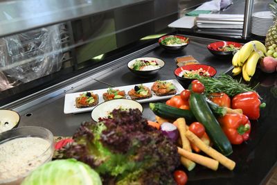 Frisches Gemüse, Obst und Fertiggerichte, die auf einer Arbeitsfläche in einer Küche angerichtet sind und eine Vielfalt an farbenfrohen Lebensmitteln zeigen.