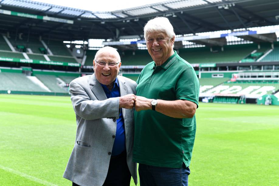 Uwe Seeler und Max Lorenz stehen im Weserstadion. Sie geben sich gegenseitig eine Faust.