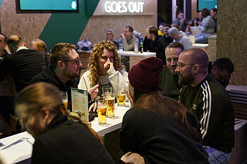 Menschen beim Quizabend an einem Tisch auf der Grünen Bude.