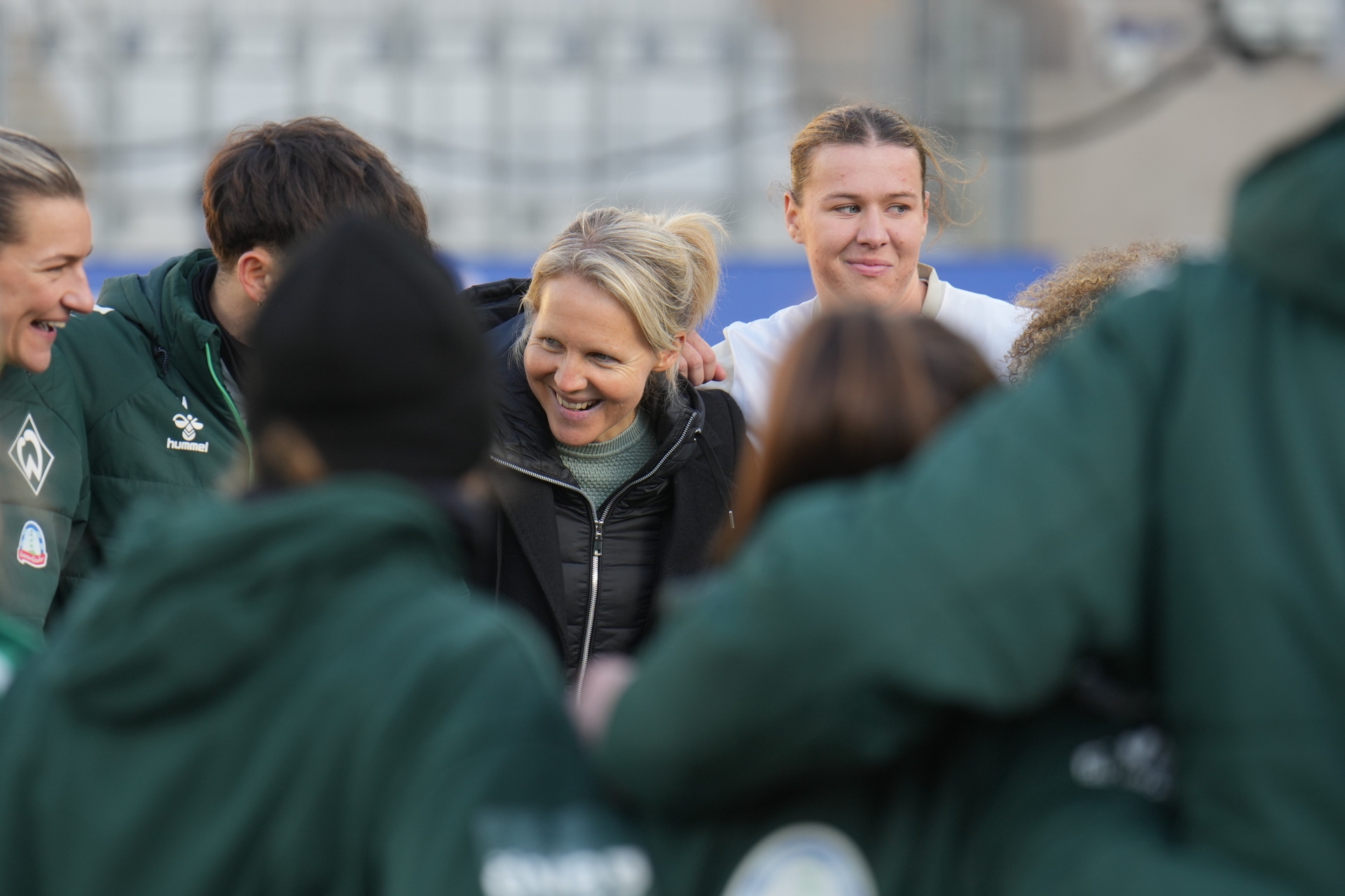 Fritzy Kromp lacht im Mannschaftskreis. Neben ihr stehen Larissa Mühlhaus und Medina Desic.