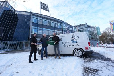 Drei Männer stehen vor einem weißen Lieferwagen mit der Aufschrift „Die Bremer Suppenengel“ in der Nähe eines Gebäudes, umgeben von Schnee.