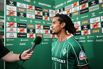 Isaac Schmidt wird von WerderTV in der Mixed Zone interviewed und lächelt. 