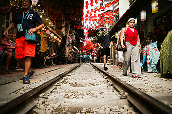 Bahngleise in Hanoi, die direkt an Hauswänden von Cafés vorbeiführen. 