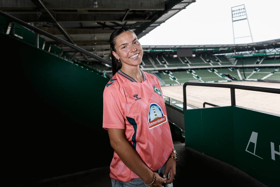 Luna Vanzier im neuen Werder "Trikot third". Sie steht im Weserstadion auf den Rängen. Im Hintergrund sieht man ein Flutlicht.
