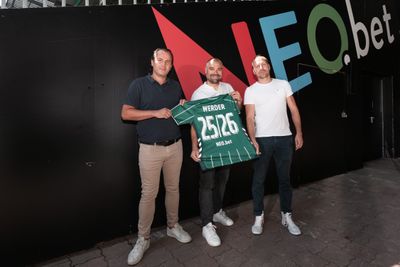 Mehrere Personen stehen vor einer Wand mit neobet-Aufdruck. Sie halten ein Werder-Trikot in der Hand.