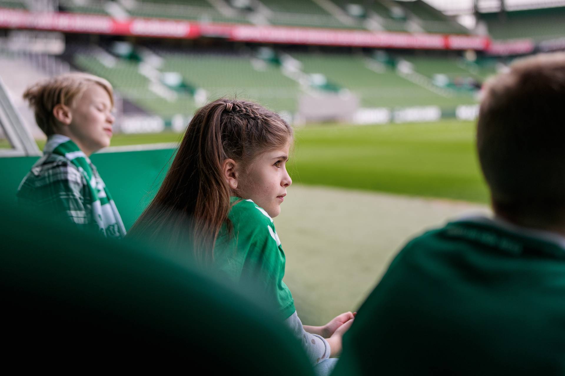 Ein Werder-Fan sitzt auf der Trainerbank und hört gespannt dem Stadionführer zu.