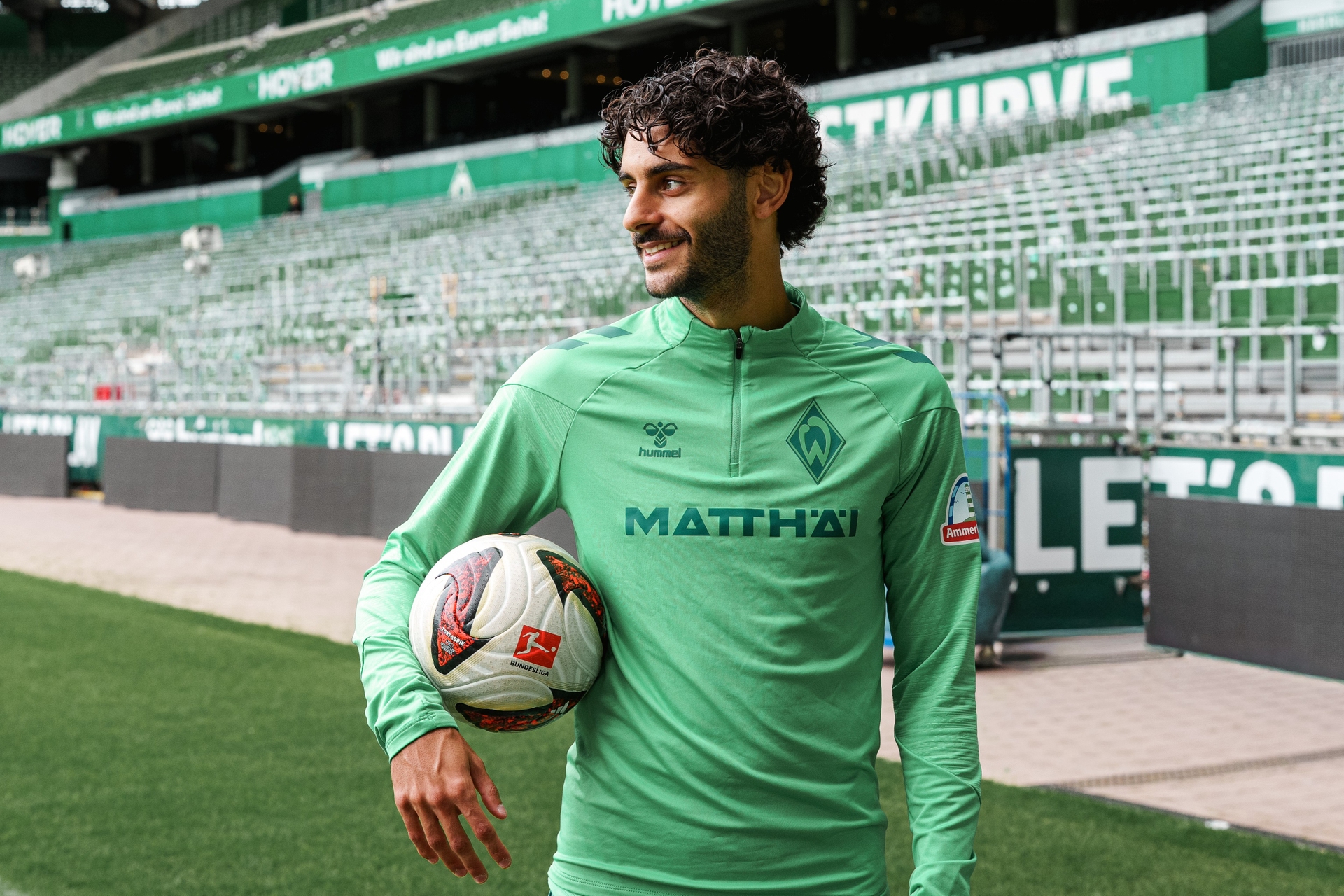 Eren Dinkçi steht mit einem Ball unter dem Arm vor der Ostkurve