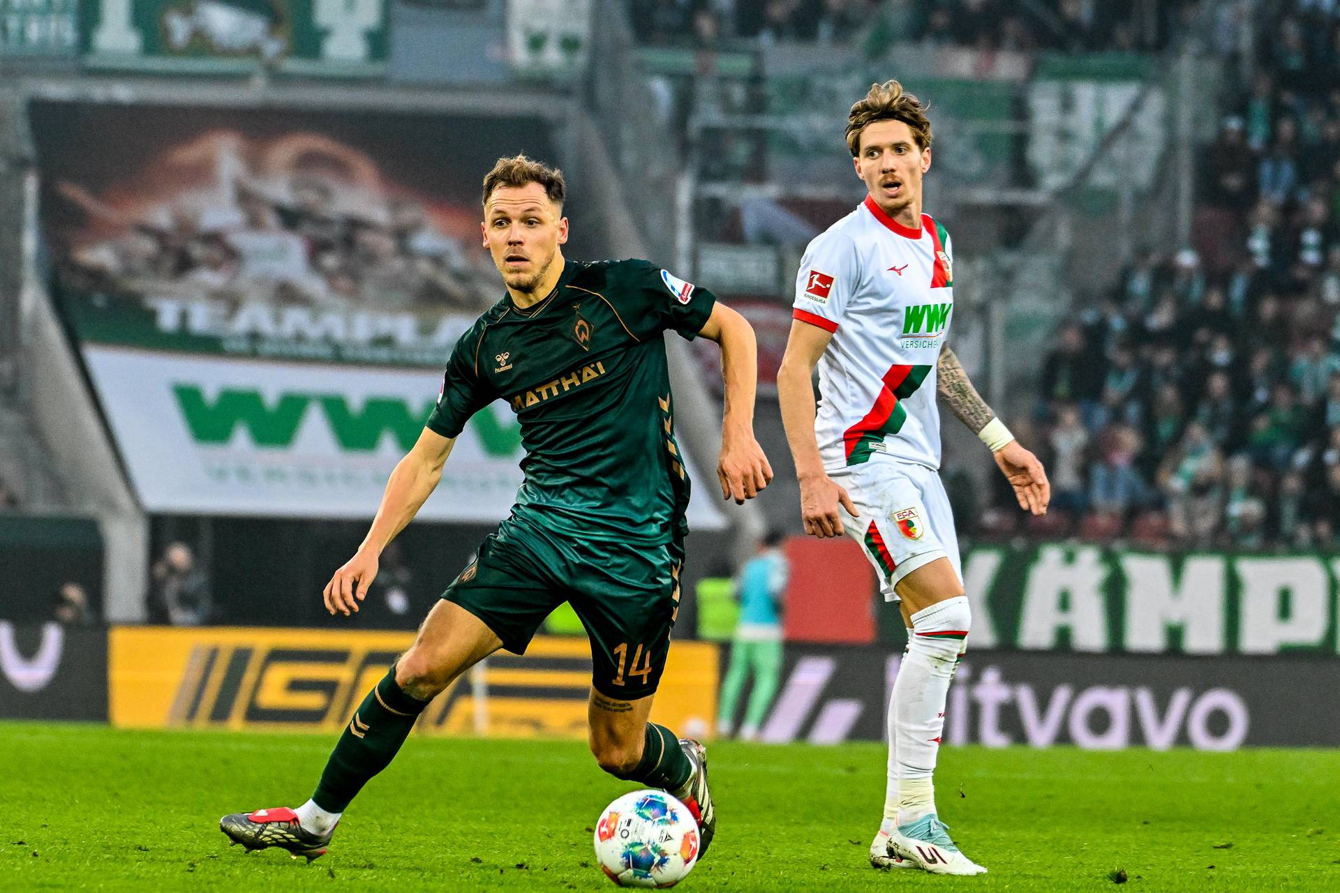 Senne Lynen mit Blick auf den Ball, im Hintergrund ein Augsburger.