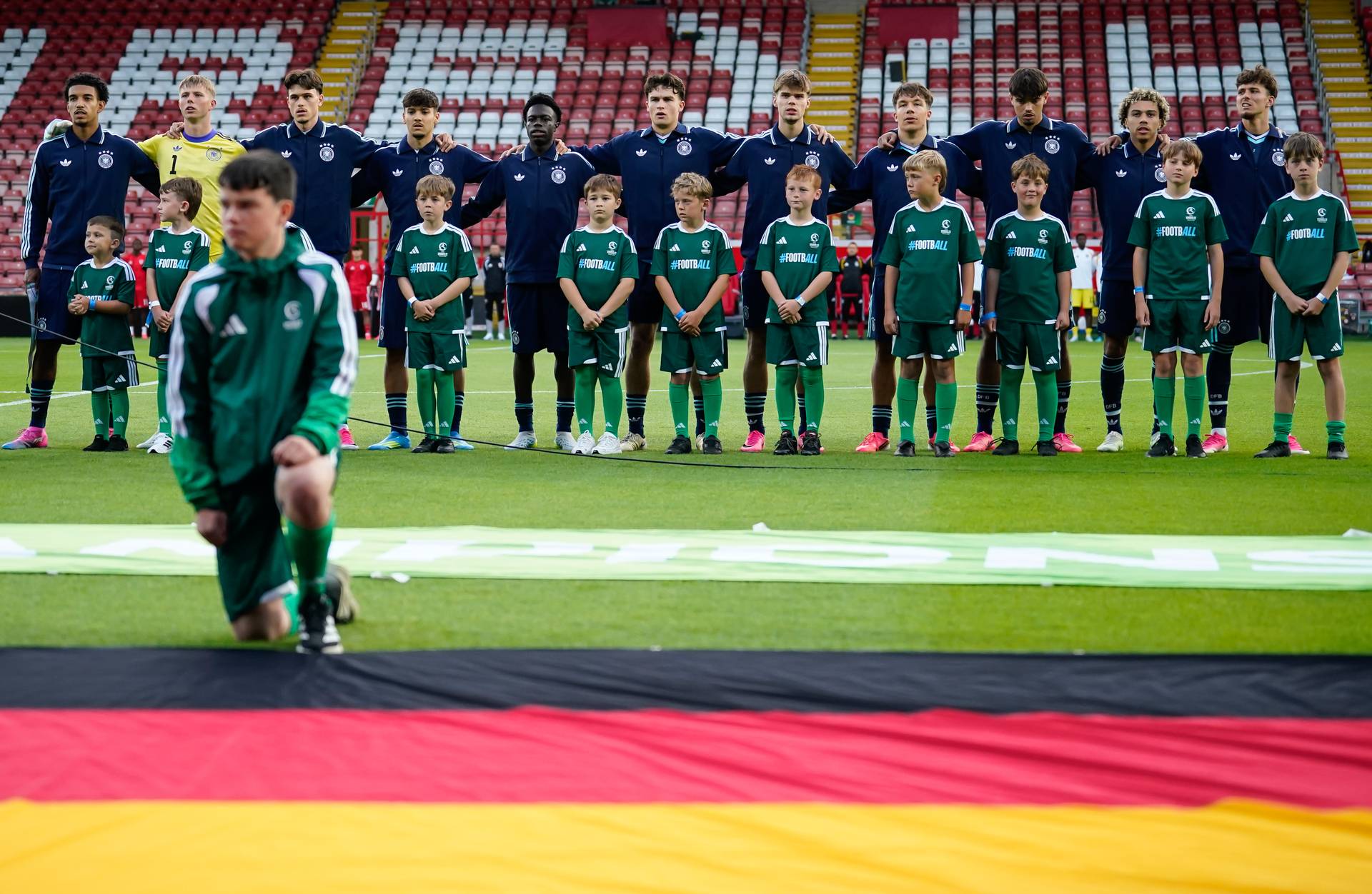 Die Nationalspieler der U19 des DFB stehen gemeinsam vor der deutschen Flagge.