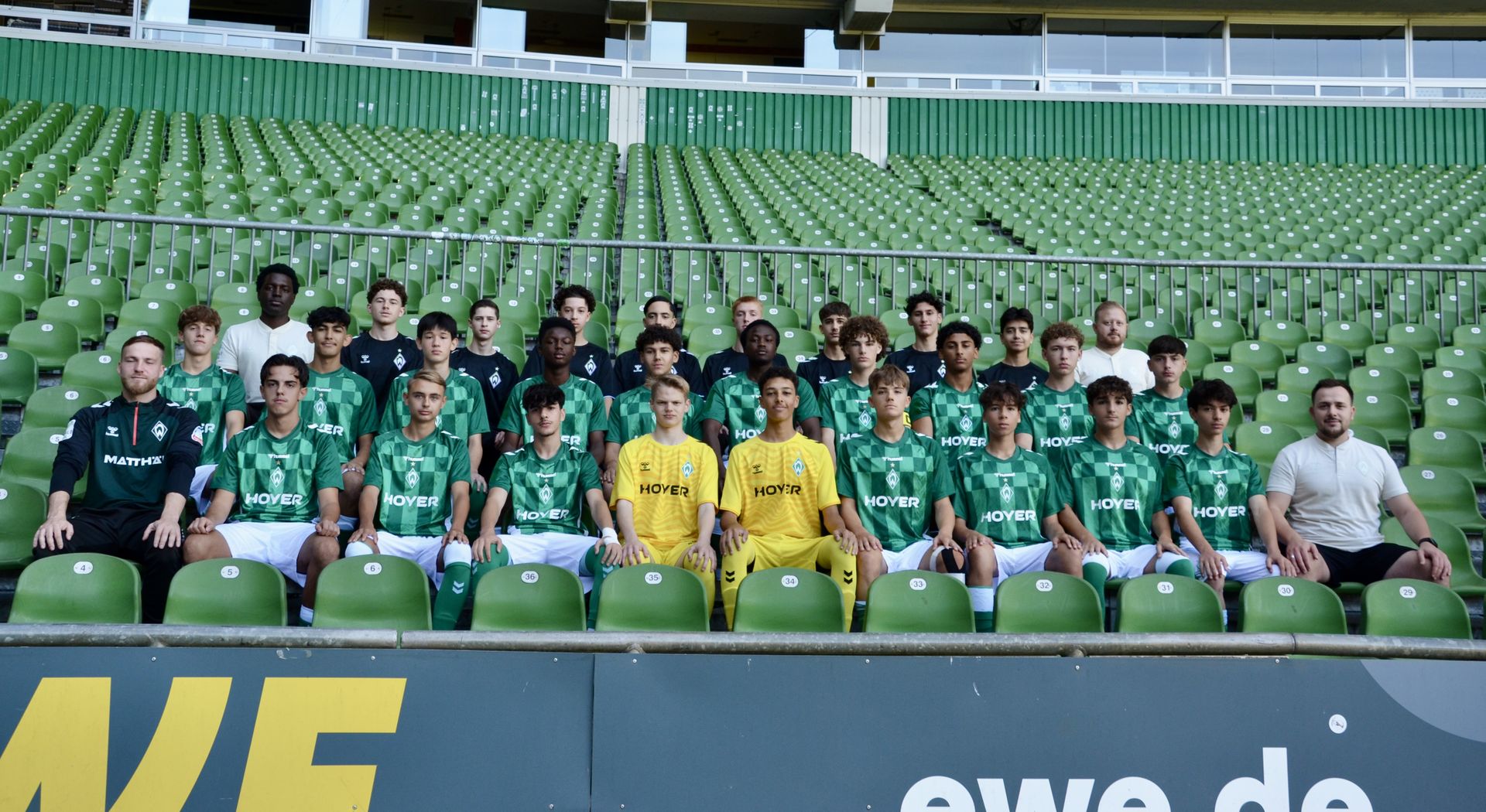 Ein Mannschaftsfoto. Die Spieler und das Trainerteam sitzen auf der Tribüne.