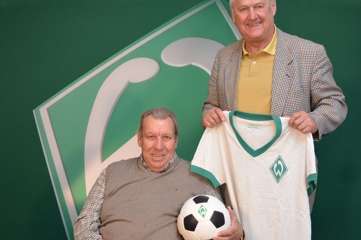 Horst-Dieter Höttges sitzt und Max Lorenz steht daneben. Im Hintergrund eine Werder-Raute.