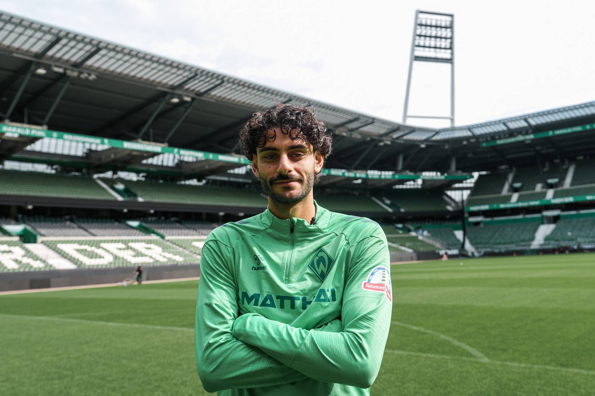 Eren Dinkçi steht mit verschränkten Armen im leeren Weserstadion.