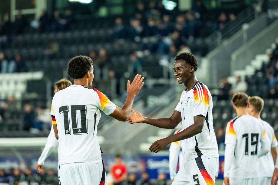 Karim Coulibaly klatscht im Nationalspieler mit einem Teamkollegen ab.