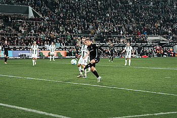 Keke Topp schießt, hinter ihm steht ein Gladbacher Spieler.