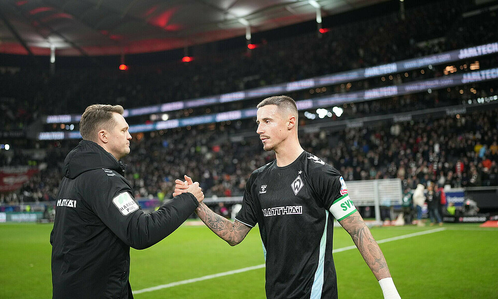 Kapitän Marco Friedl klatscht mit Physio Claas Bente nach dem Spiel bei Eintracht Frankfurt ab.