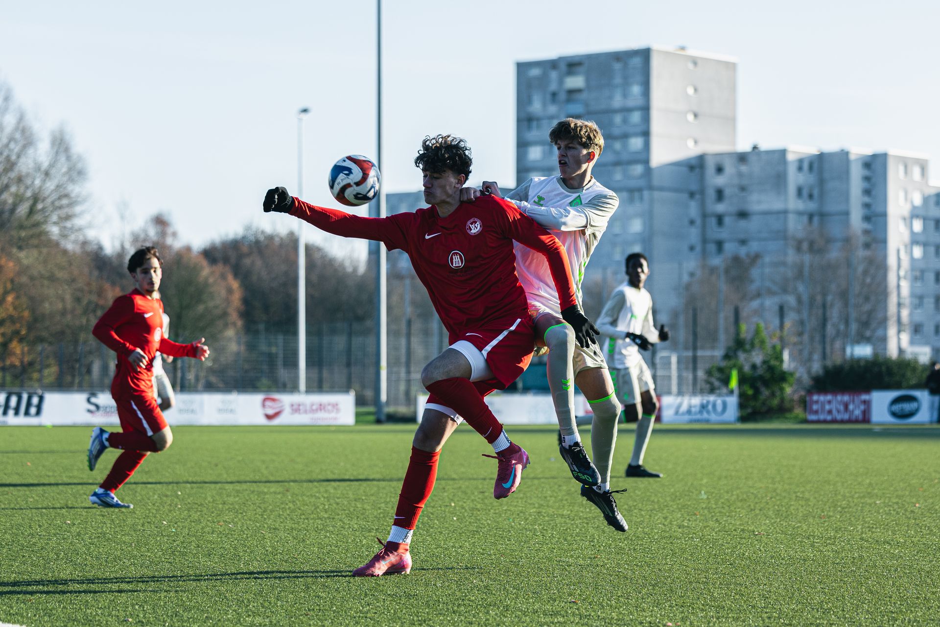 Ein Spieler der U16 und ein Gegenspieler springen in die Luft, um den Ball vor ihnen zu erreichen.