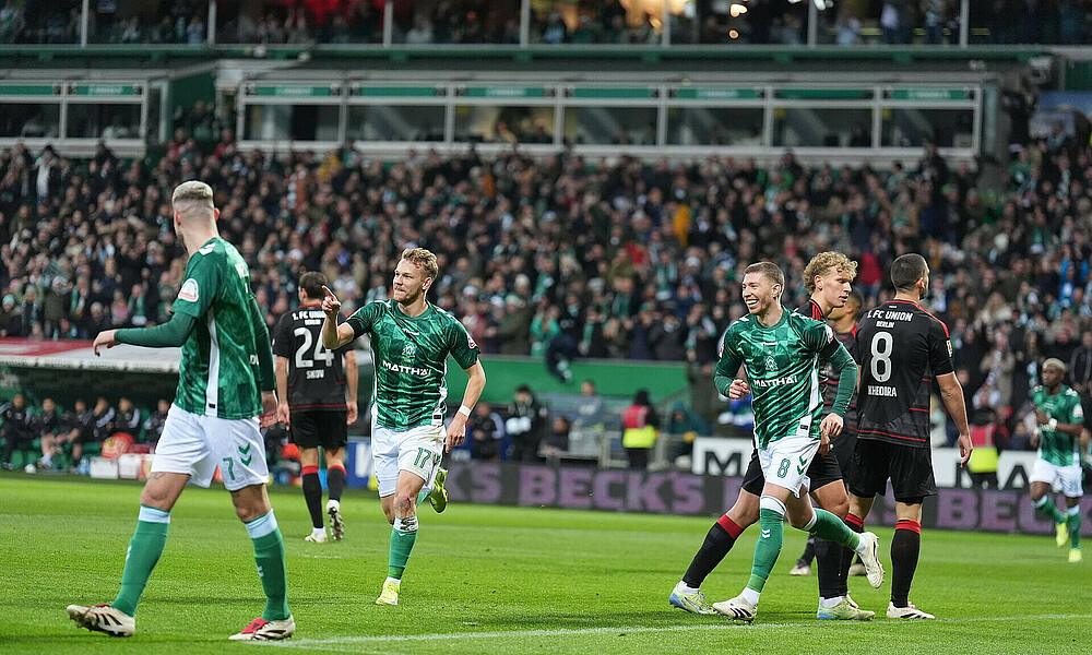 null Naby Keïta lächelt mit Ball in der Hand.