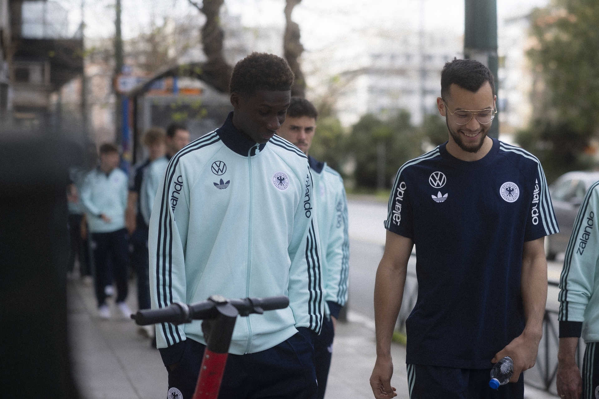 Karim Coulibaly im Trainingsanzug bei einem Spaziergang mit Mio Backhaus im DFB-Outfit.