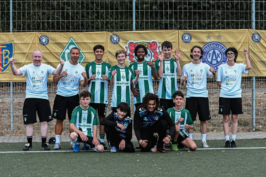 Das Werder Team, in den neuen Heimtrikots post zusammen auf einem Fußballplatz, im Hintergrund sind die Logos der teilnehmenden Clubs