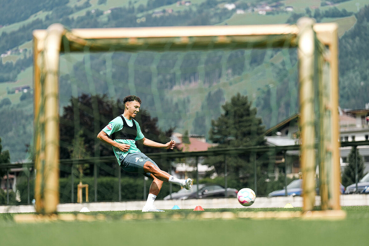 Lee Buchanan nimmt einen Ball an, das Bild ist durch ein Tornetz fotografiert.