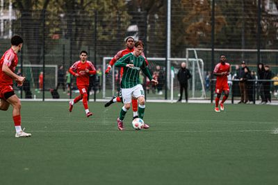 Ein U16 Spieler dribbelt im grünen Werder-Dress von de Gegenspielern weg.
