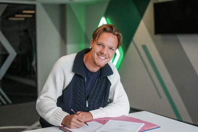 Jakob Wiehe sitzt an einem Tisch und unterschreibt einen Vertrag.