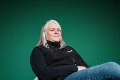 Birte Brüggemann sitzt vor einem grünen Hintergrund und lächelt.