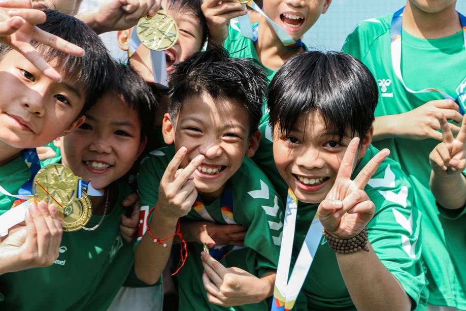 Eine Gruppe aus lächelnden Kindern in grünen Werder Trikots halten Goldmedaillen hoch