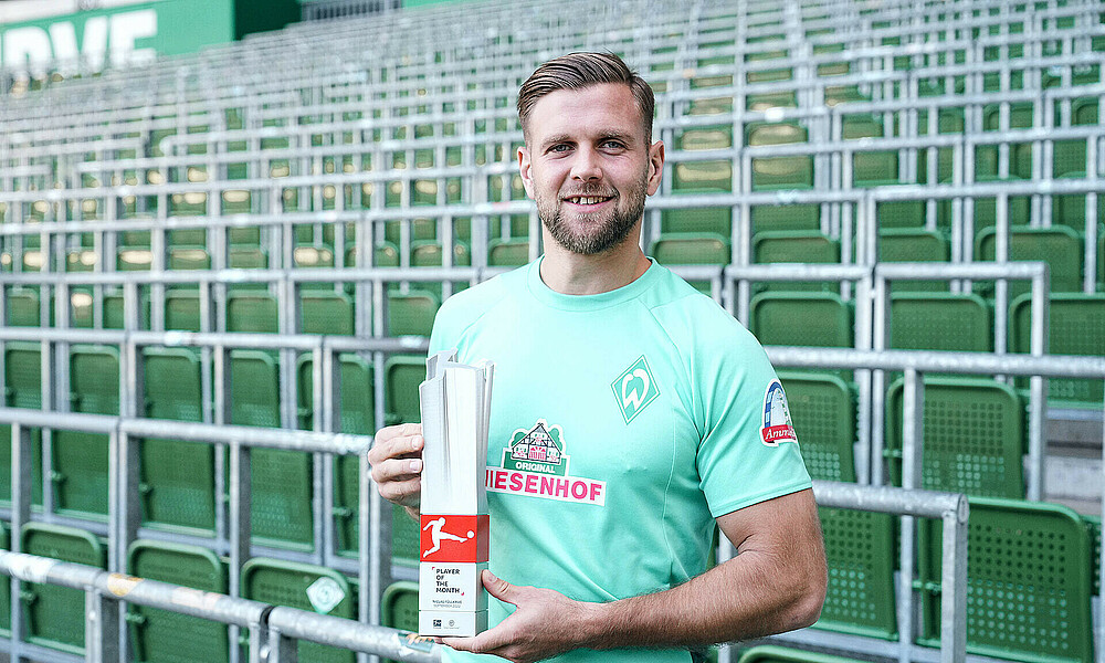 Niclas Füllkrug hält die Trophäe zum Player of the Month