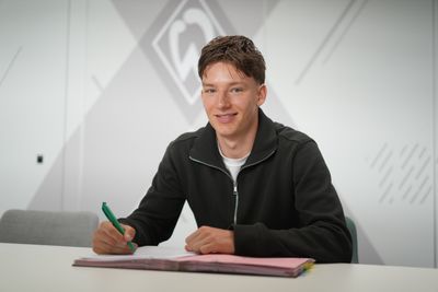Karlo Simic sitzt mit einem Stift in der Hand und einem Vertrag vor sich liegend an einem Tisch.
