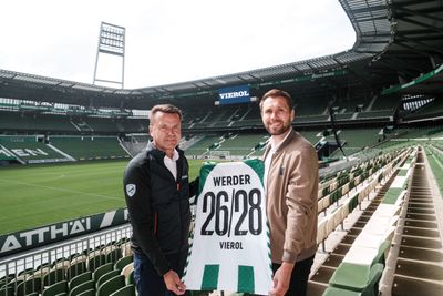 Zwei Männer stehen im Weserstadion und halten ein Werder-Trikot hoch.