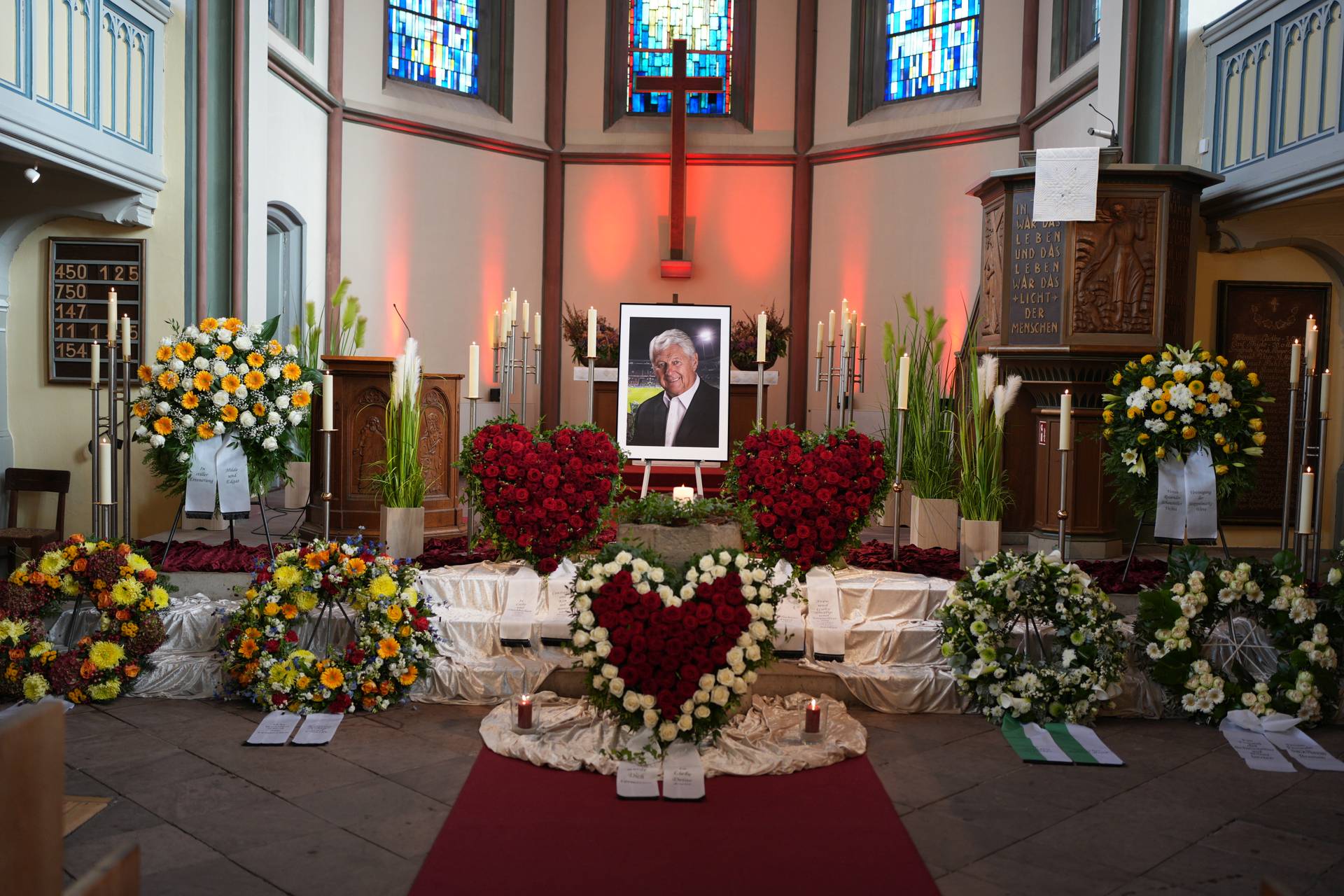 Ein Blick in die Kirche, in der die Trauerfeier stattfindet. Dort sind Blumen niedergelegt sowie ein Portrait von Max Lorenz zu sehen.