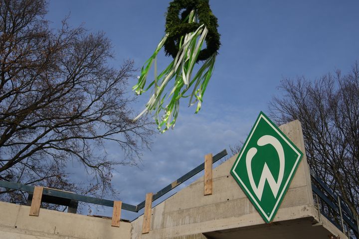 Ein Kranz, der über eine Werder-Raute mit einem Bagger gehoben wird.