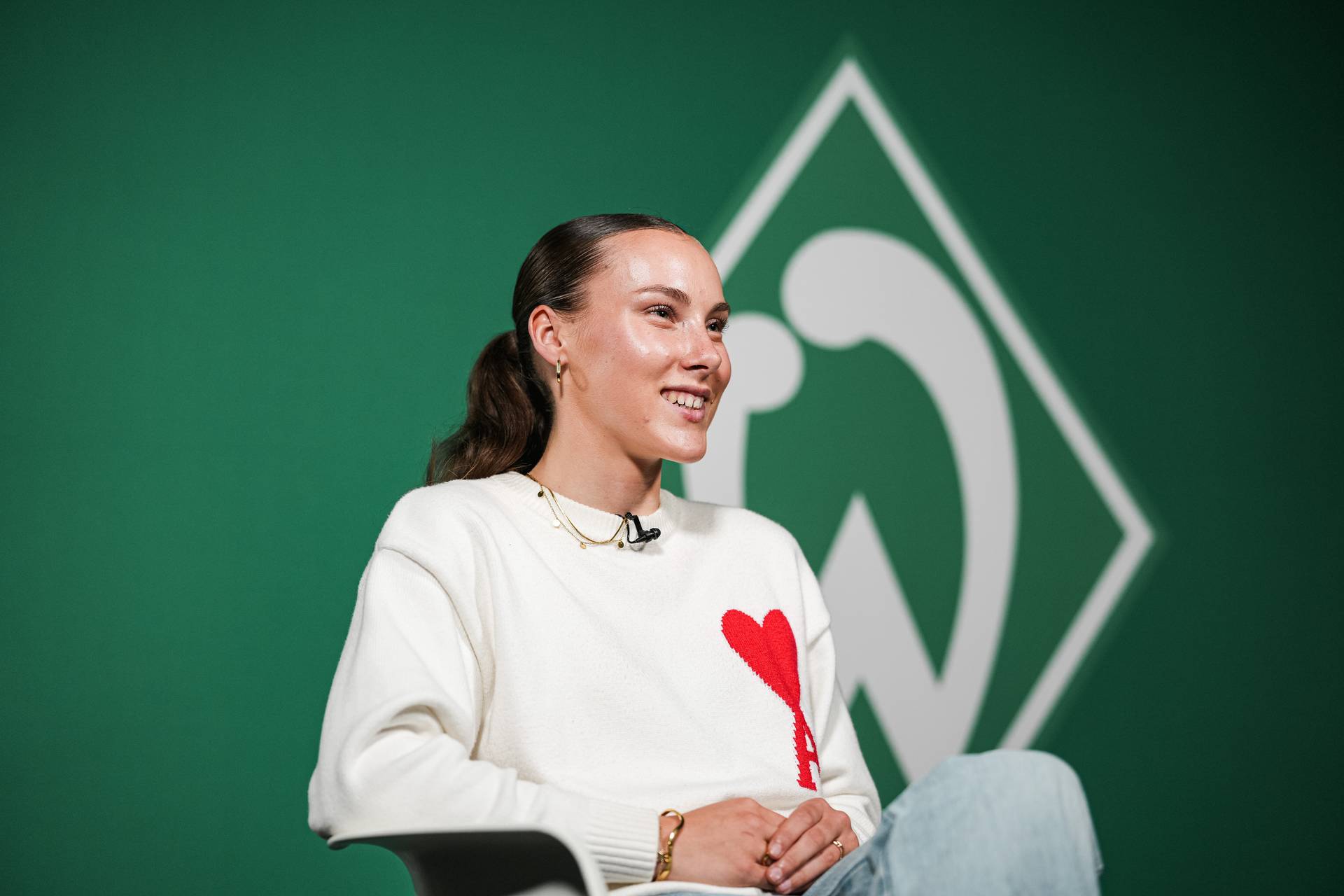 Felicia Sträßer sitzt vor einer Werder-Raute.