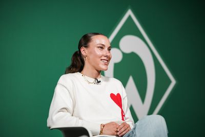 Felicia Sträßer sitzt vor einer Werder-Raute.