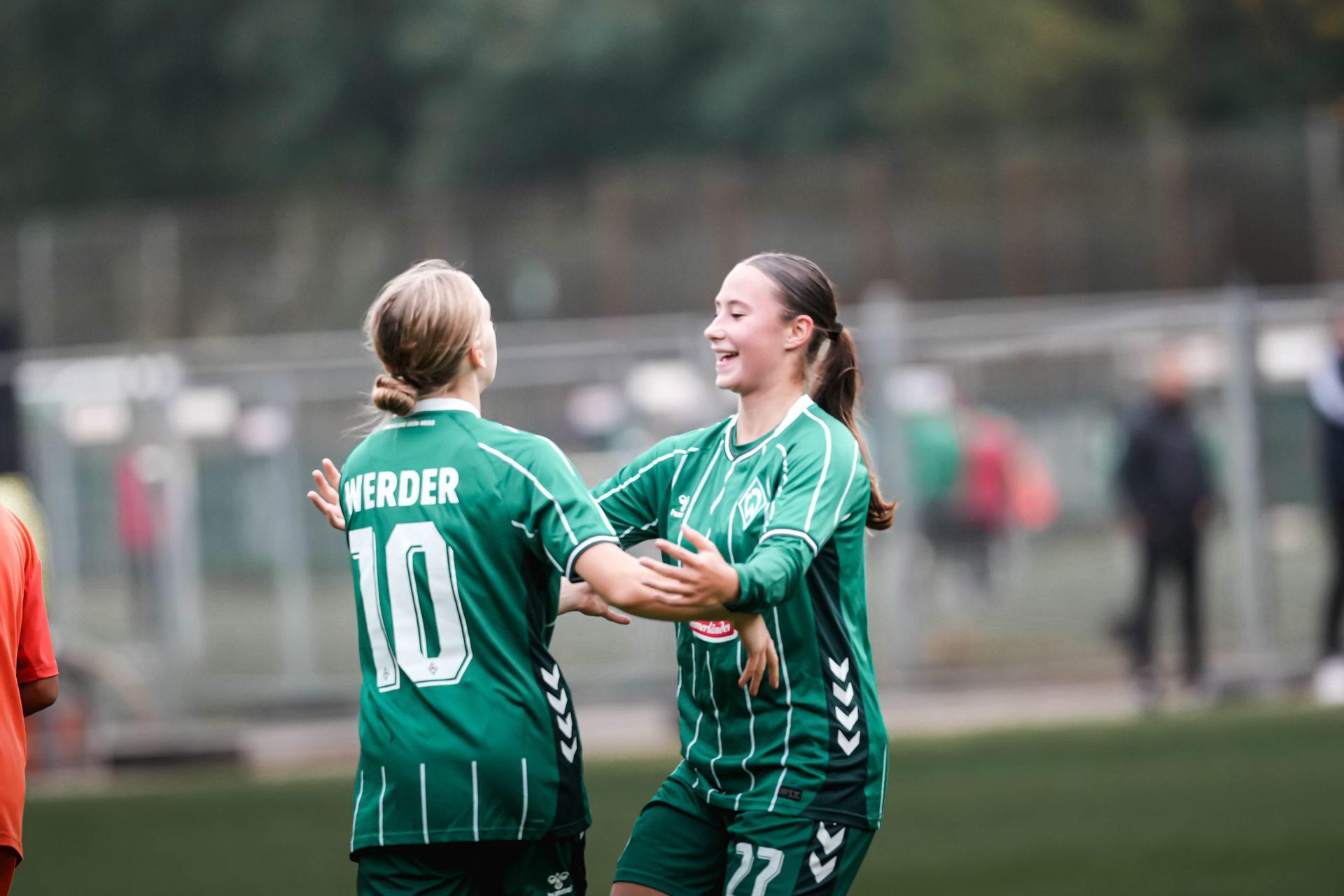 Zwei U17-Spielerinnen feiern gemeinsam ein Tor und möchten sich umarmen.