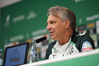 Horst Steffen lächelt bei der Pressekonferenz auf dem Podium.