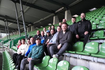 Eine Gruppe von Menschen sitzt auf grünen Stühlen auf der Tribüne im Weserstadion.