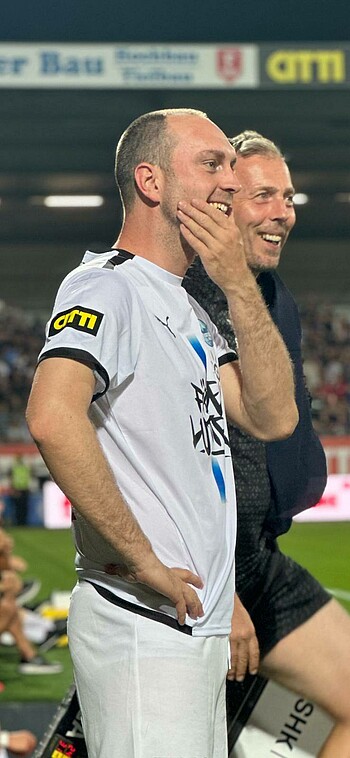 Ole Werner grinst und fässt sich mit einer Hand ans Kinn.