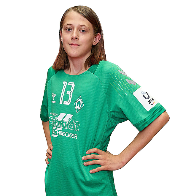 Eine junge Frau im grünen Sport-Shirt mit der Nummer 13 drauf, sie stemmt die Arme in die Hüften und lächelt.