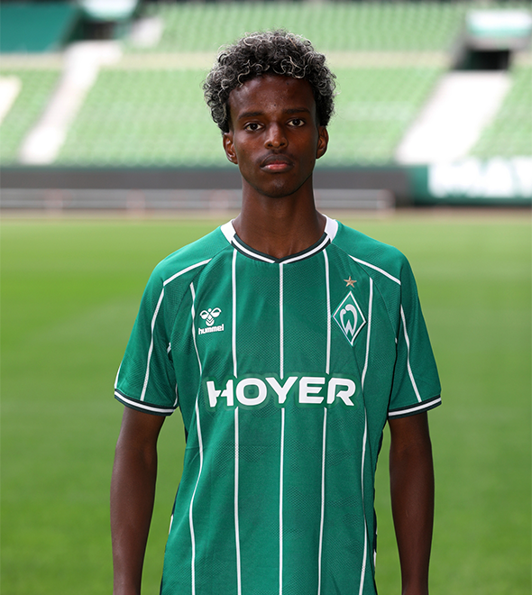 Portrait von Mahamed Mahamud. Er stemmt die Hände in die Hüften.