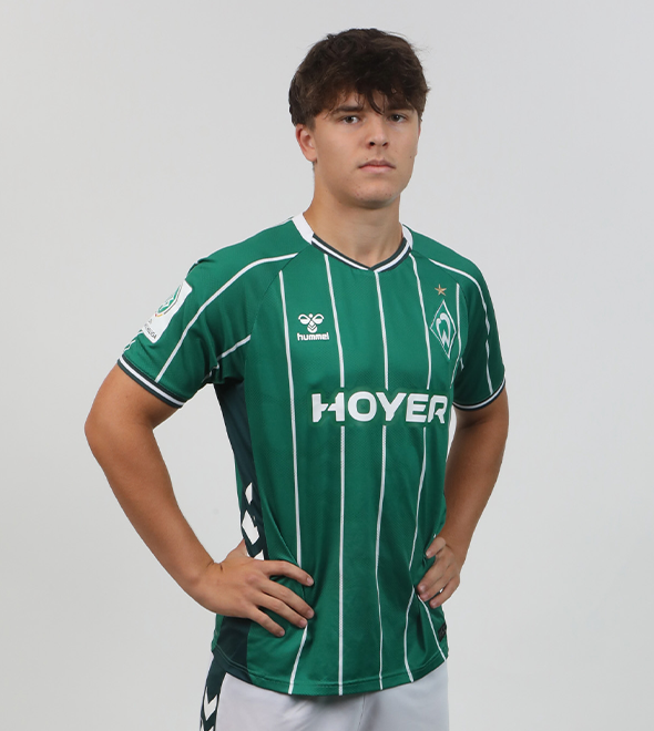 Portrait von Bennett Warschke. Er stemmt die Hände in die Hüften.