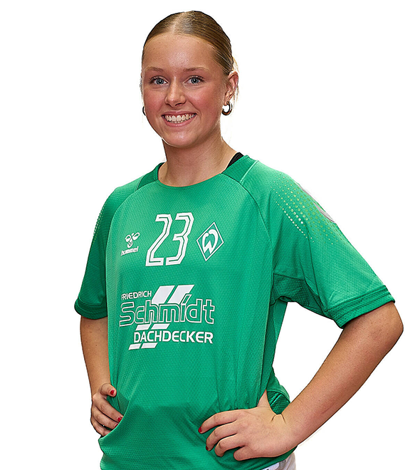 Eine junge Frau im grünen Sport-Shirt mit der Nummer 23 drauf, sie stemmt die Arme in die Hüften und lächelt.