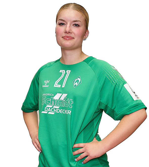 Eine junge Frau im grünen Sport-Shirt mit der Nummer 21 drauf, sie stemmt die Arme in die Hüften und lächelt.